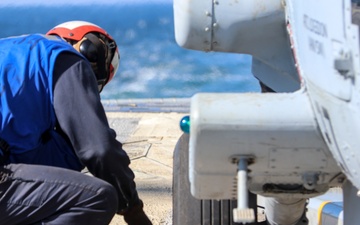 BM3 Carlens Milice removes the chocks and chains prior to an MH-60R Seahawk take-off during the Northern Coasts 2025