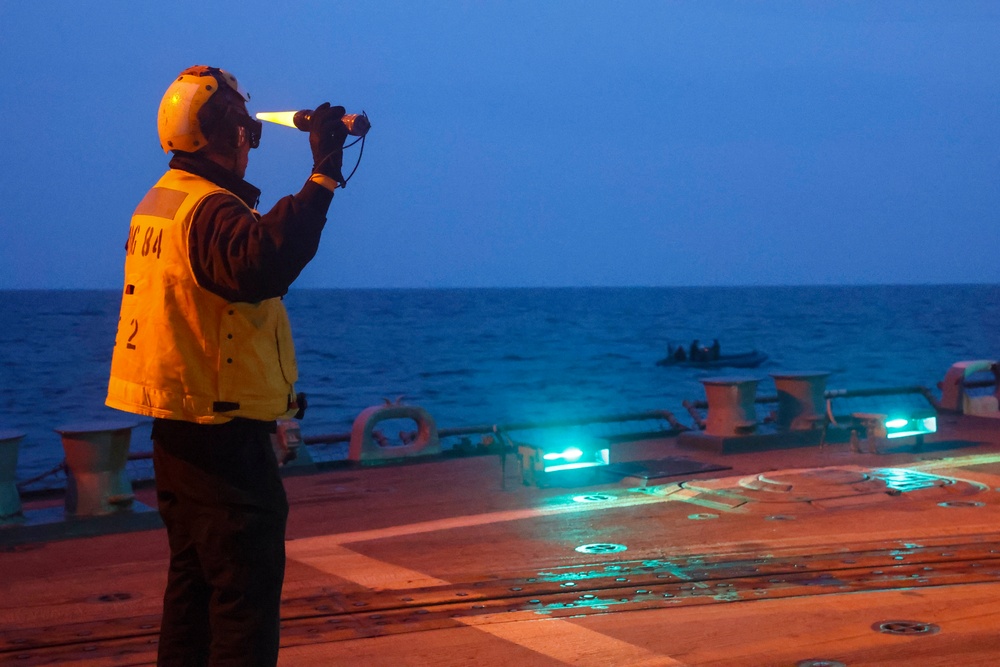 BM1 Jason Carpenter signals to pilots while a rigid-hulled inflatable boat team executes maneuvers during exercise Northern Coasts 2025