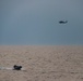 A MH-60R Sea Hawk helicopter conducts maneuvers alongside a rigid-hulled inflatable boat during exercise Northern Coasts 2025