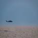 A MH-60R Sea Hawk helicopter conducts search-and-rescue training alongside a rigid-hulled inflatable boat during exercise Northern Coasts 2025