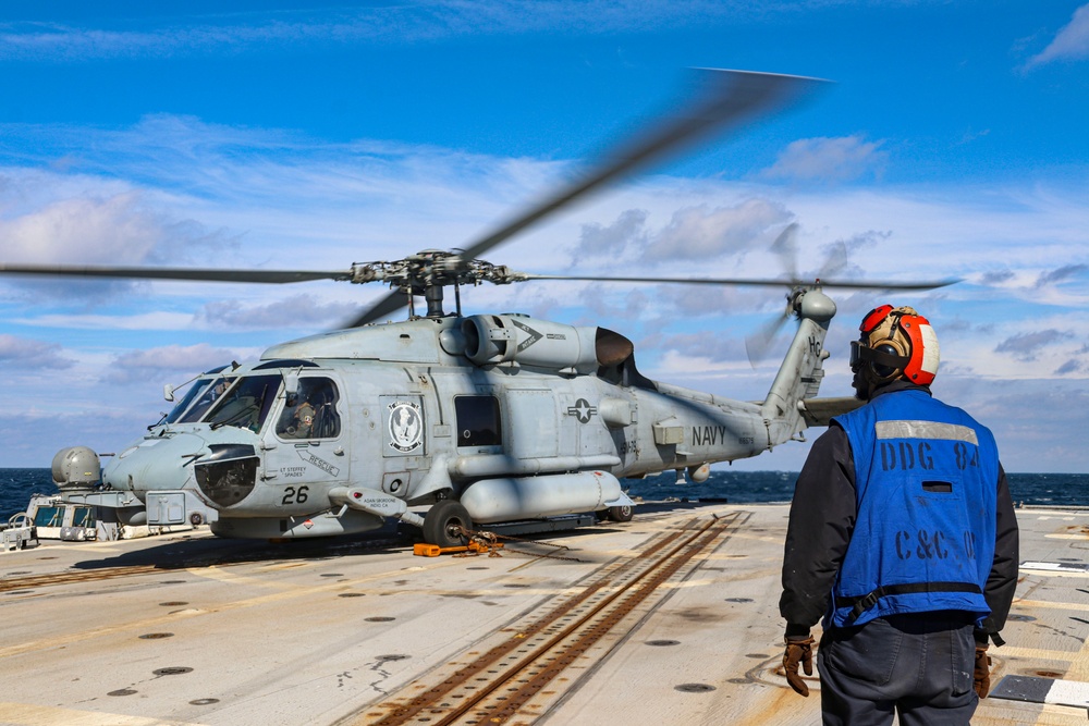 BM3 Carlens Milice awaits the signal to remove chock and chains from the MH-60R Sea Hawk helicopter during exercise Northern Coasts 2025