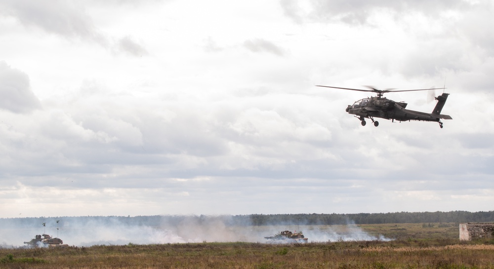 U.S. Apache flies over Abrams tanks during Iron Defender-25