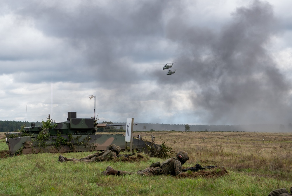 Polish soldiers take defensive positions with Hind helicopters overhead