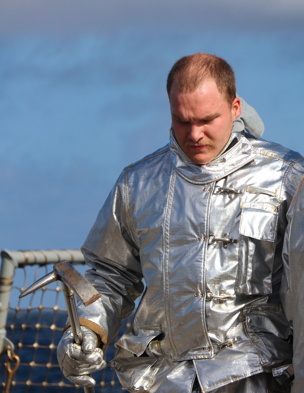 DC3 Levi Nuslein carries a pick-axe while wearing a hot suit during simulated crash and salvage training