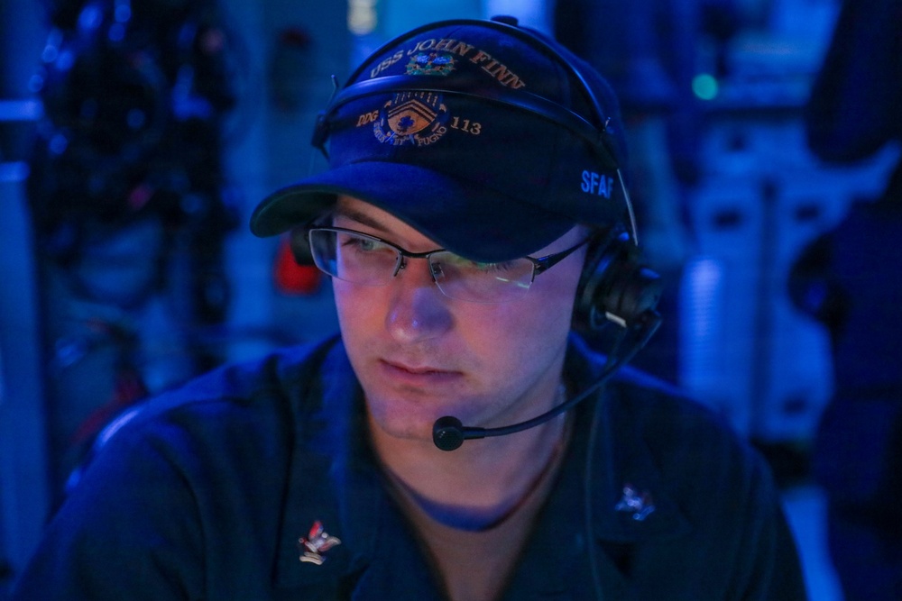 Sailors aboard the USS John Finn stand watch in the combat information center during Resolute Dragon 25 in the Philippine Sea