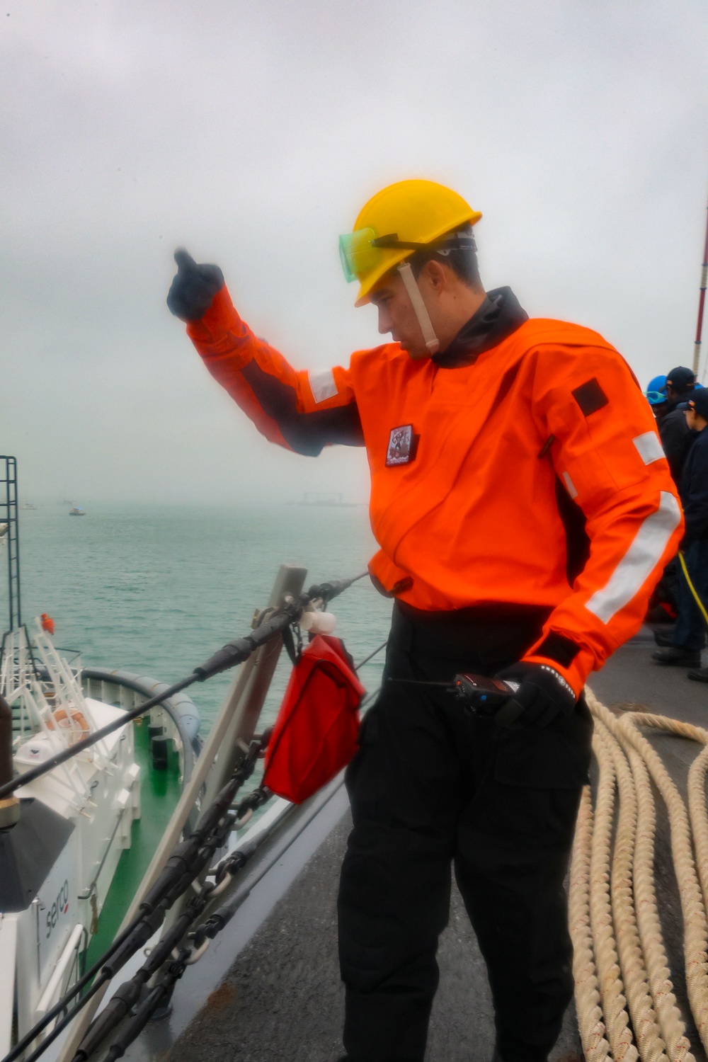 BM1 Jason Carpenter signals to coordinate with a tugboat line handler