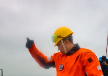 BM1 Jason Carpenter signals to coordinate with a tugboat line handler