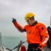 BM1 Jason Carpenter signals to coordinate with a tugboat line handler
