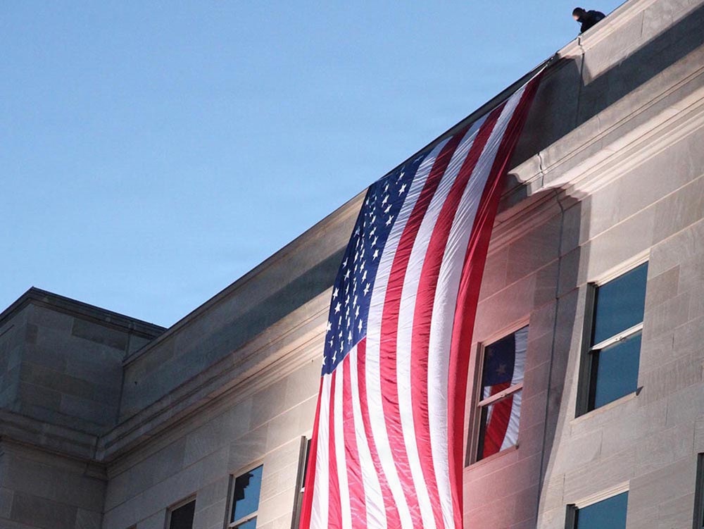 An American flag hangs from the side of the Pentagon building