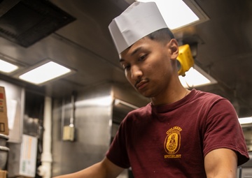 USS Mitscher (DDG 57) Sailor prepares food in ships galley