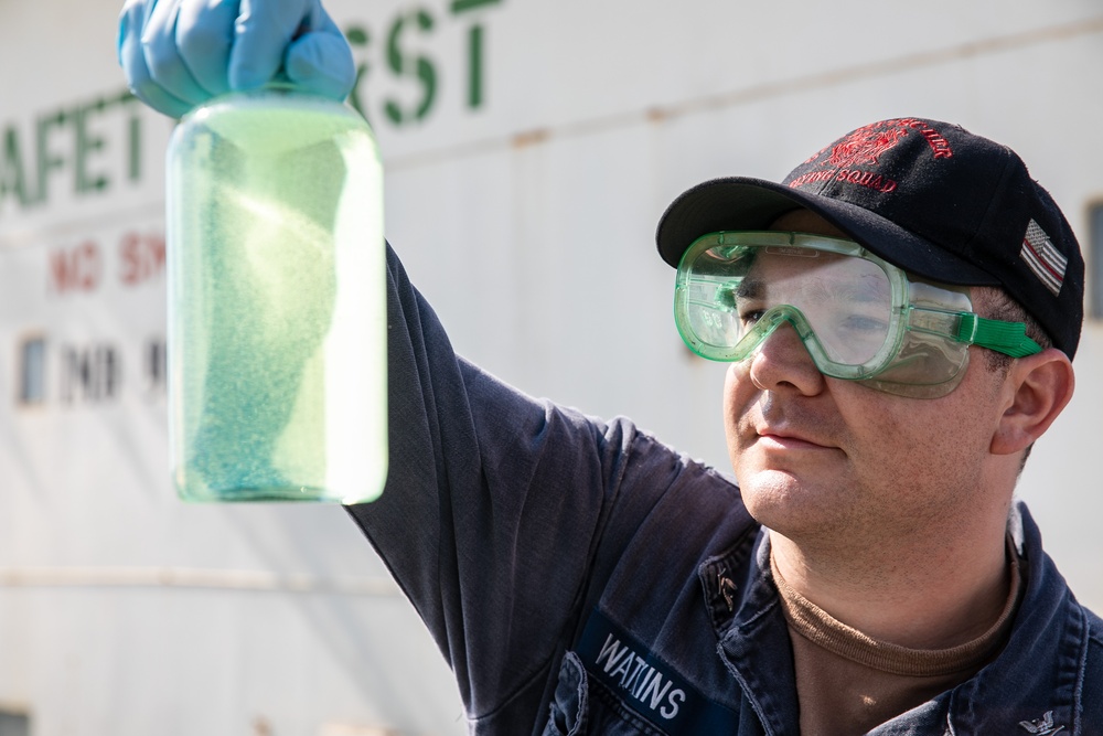 USS Mitscher (DDG 57) Sailor inspects fuel sample during refueling