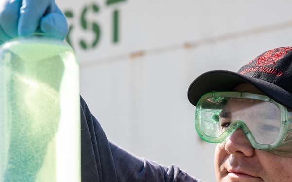 USS Mitscher (DDG 57) Sailor inspects fuel sample during refueling