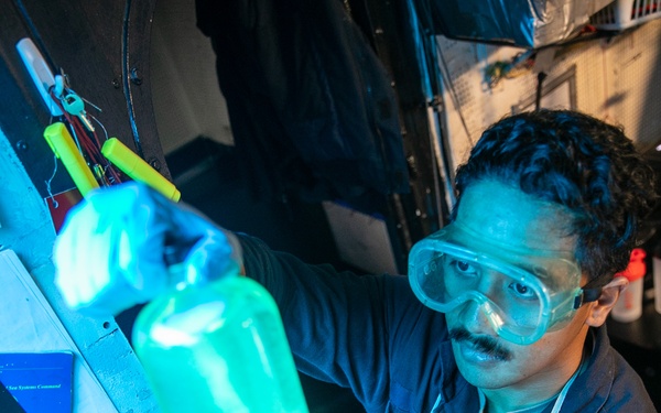 USS Mitscher (DDG 57) Sailor inspects fuel sample in oil laboratory