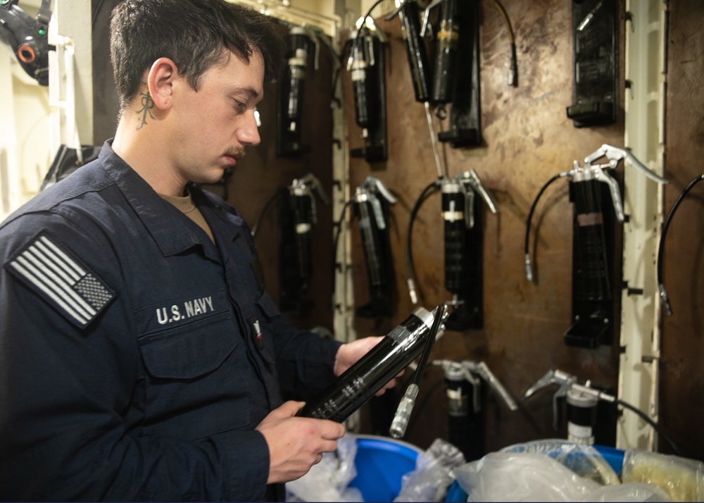 USS Mitscher (DDG 57) Sailor inspects HAZMAT in storage locker