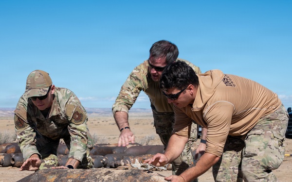Airmen from the 377th Air Base Wing Explosive Ordnance Disposal Flight Maneuver an Unexploded Training Munition