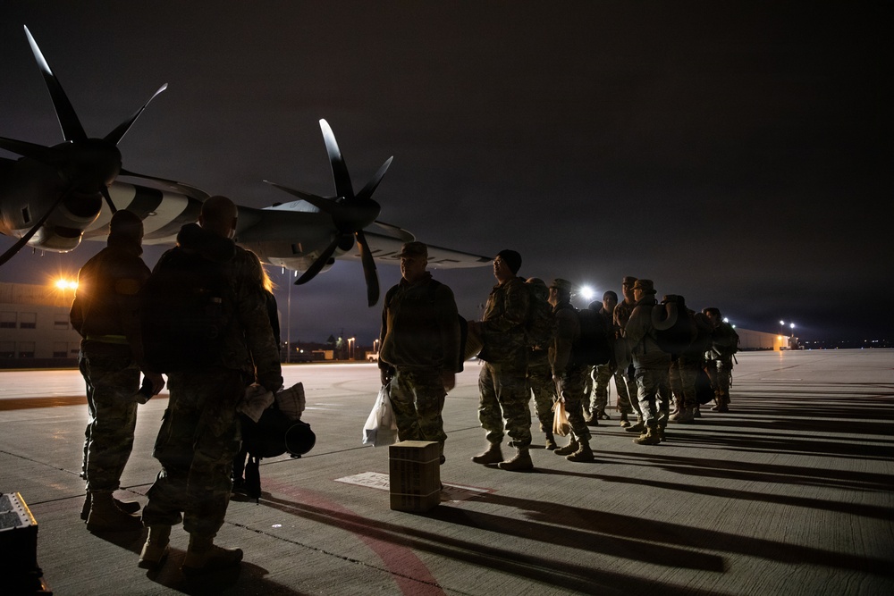 Soldiers of the 147th Army Band, South Dakota Army National Guard, wait to board a Kentucky Air National Guard C-130J Super Hercules