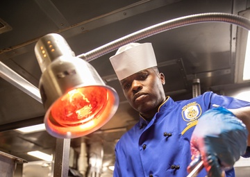 USS Mitscher (DDG 57) Sailor carves Thanksgiving turkey