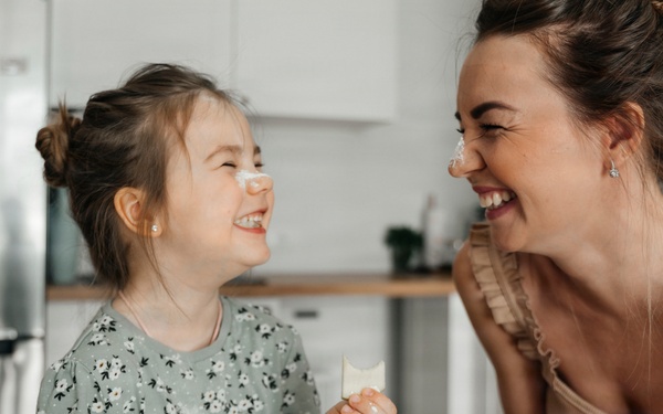 Playful mother and daughter preparing food together in kitchen