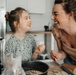 Playful mother and daughter preparing food together in kitchen