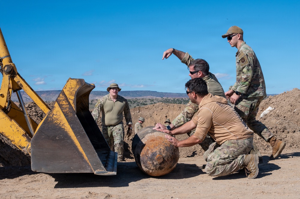Airmen from the 377th Explosive Ordnance Disposal Flight guide a recovered training munition toward heavy equipment for relocation during a clearance mission on the Pueblo of Isleta, N.M.