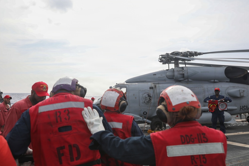 Sailors aboard the USS John Finn simulate fighting a fire during a crash and salvage drill in the Philippine Sea