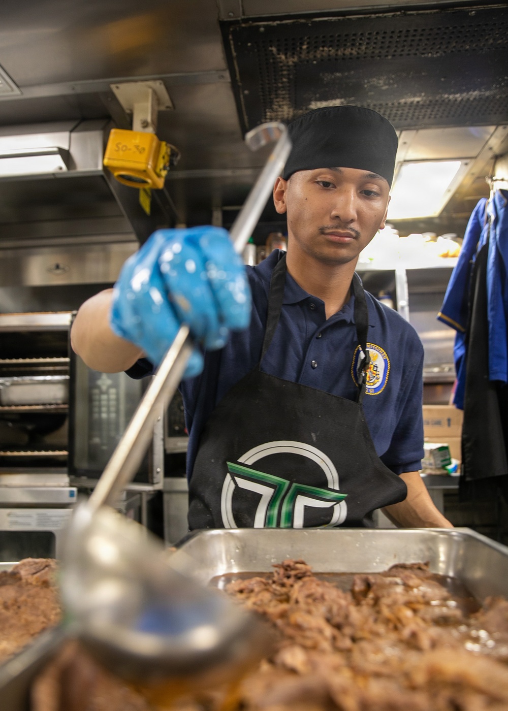 USS Mitscher (DDG 57) Sailor prepares food in ship galley