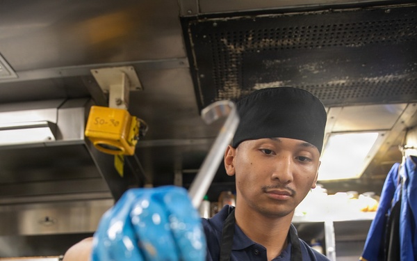 USS Mitscher (DDG 57) Sailor prepares food in ship galley