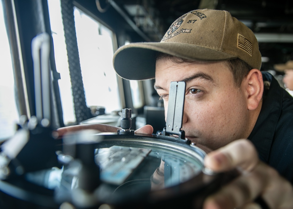 USS Mitscher (DDG 57) junior officer looks through alidade in ship bridge