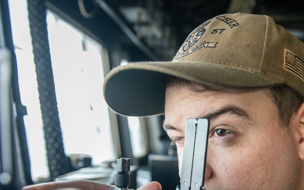 USS Mitscher (DDG 57) junior officer looks through alidade in ship bridge