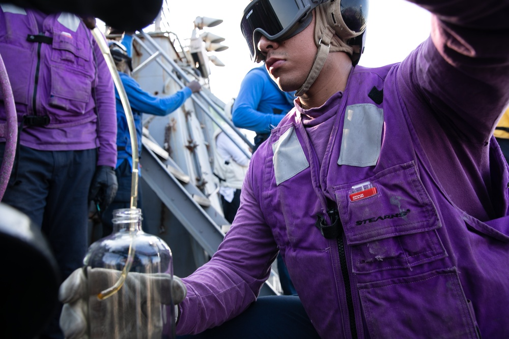 USS Mitscher (DDG 57) Sailor takes fuel sample during flight quarters