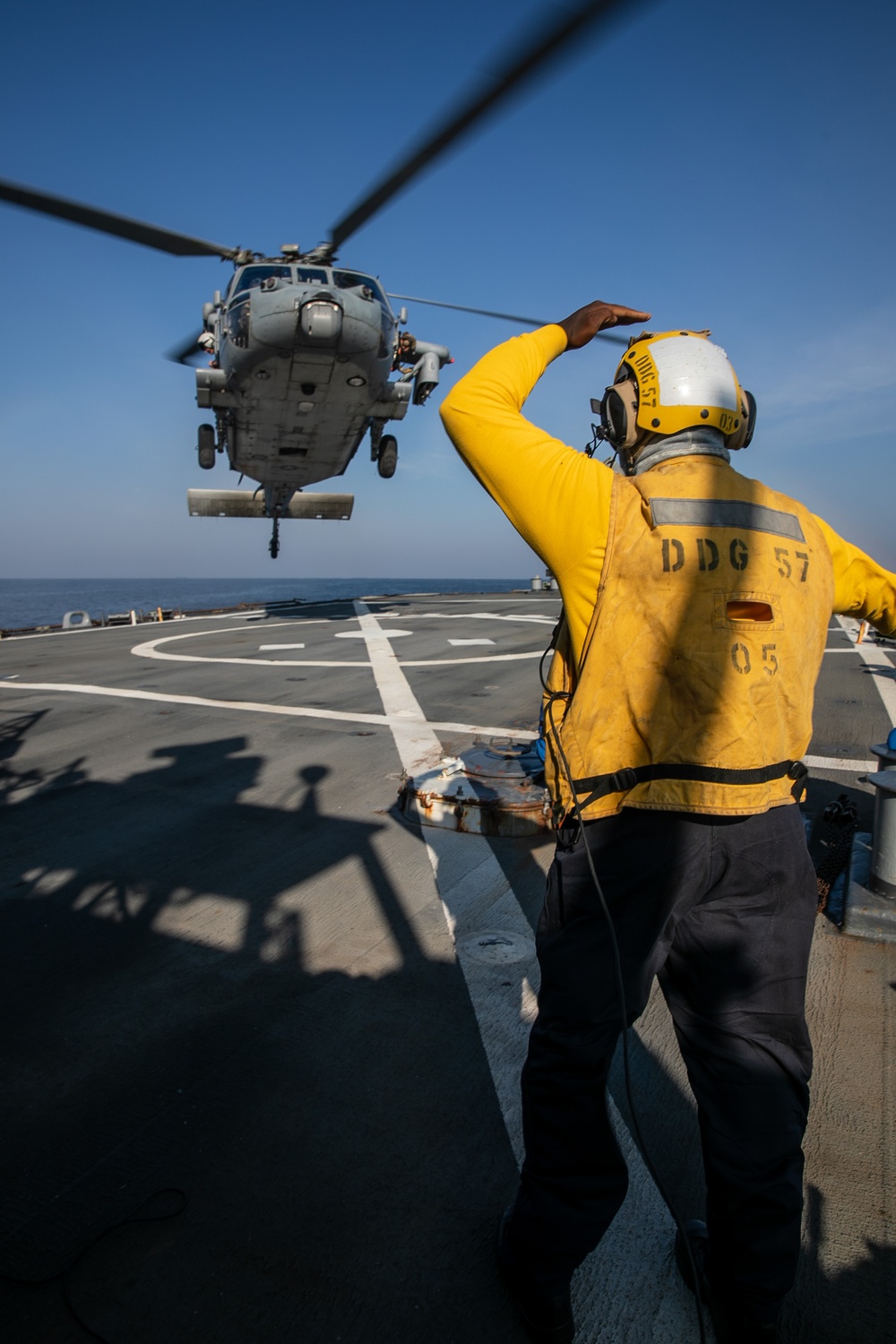 USS Mitscher (DDG 57) Sailor signals to HSM 26 Sea Hawk during flight operations