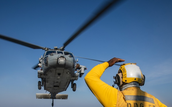 USS Mitscher (DDG 57) Sailor signals to HSM 26 Sea Hawk during flight operations
