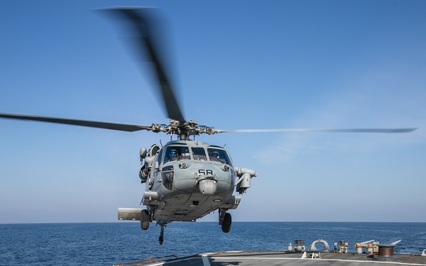 USS Mitscher (DDG 57) Sailor signals to HSM 26 Sea Hawk during flight operations