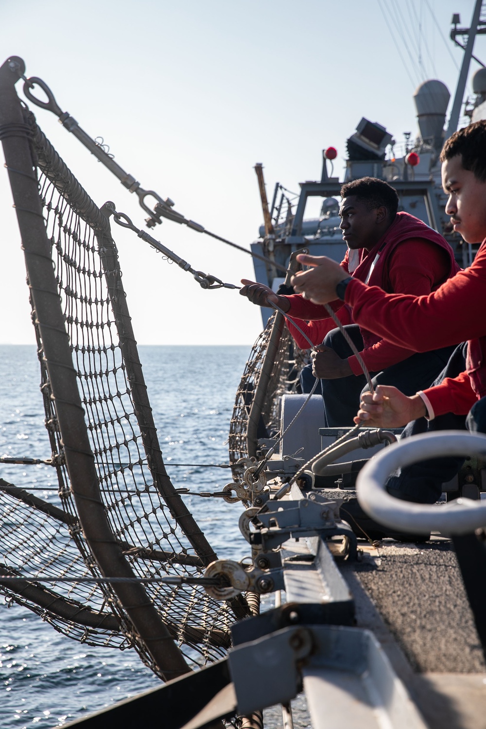 USS Mitscher (DDG 57) Sailors raise safety nets during flight quarters