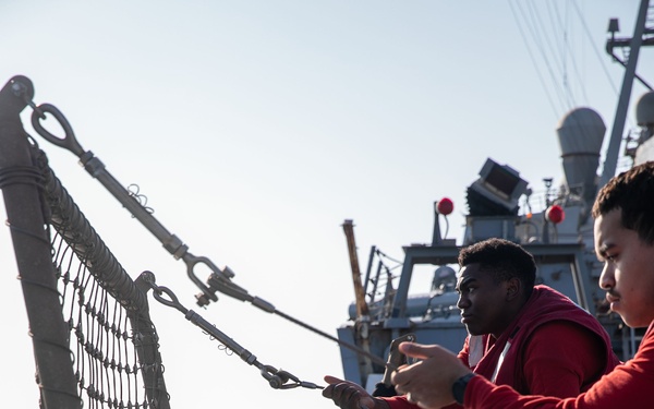 USS Mitscher (DDG 57) Sailors raise safety nets during flight quarters