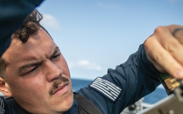 USS Mitscher (DDG 57) Sailor loads ammunition in MK 240 machine gun