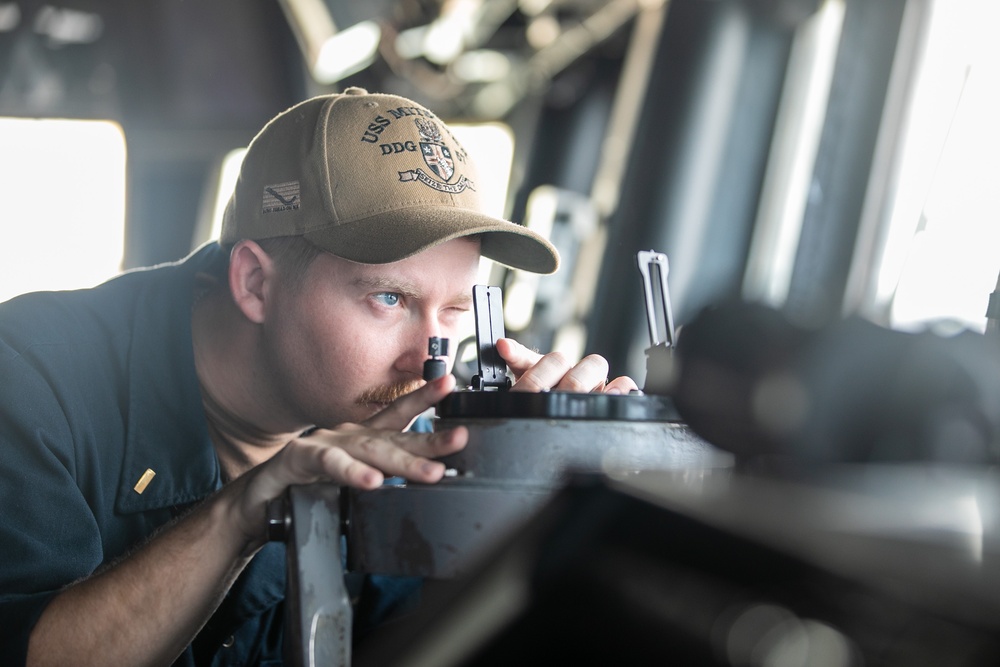 USS Mitscher (DDG 57) junior officer looks through alidade on ship bridge