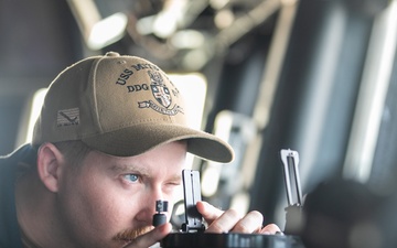 USS Mitscher (DDG 57) junior officer looks through alidade on ship bridge