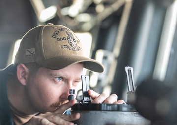 USS Mitscher (DDG 57) junior officer looks through alidade on ship bridge