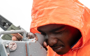 USS Mitscher (DDG 57) Sailor looks through compass on bridge wing