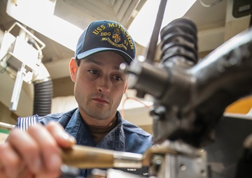 USS Mitscher (DDG 57) Sailor presses uniform items in ship laundry