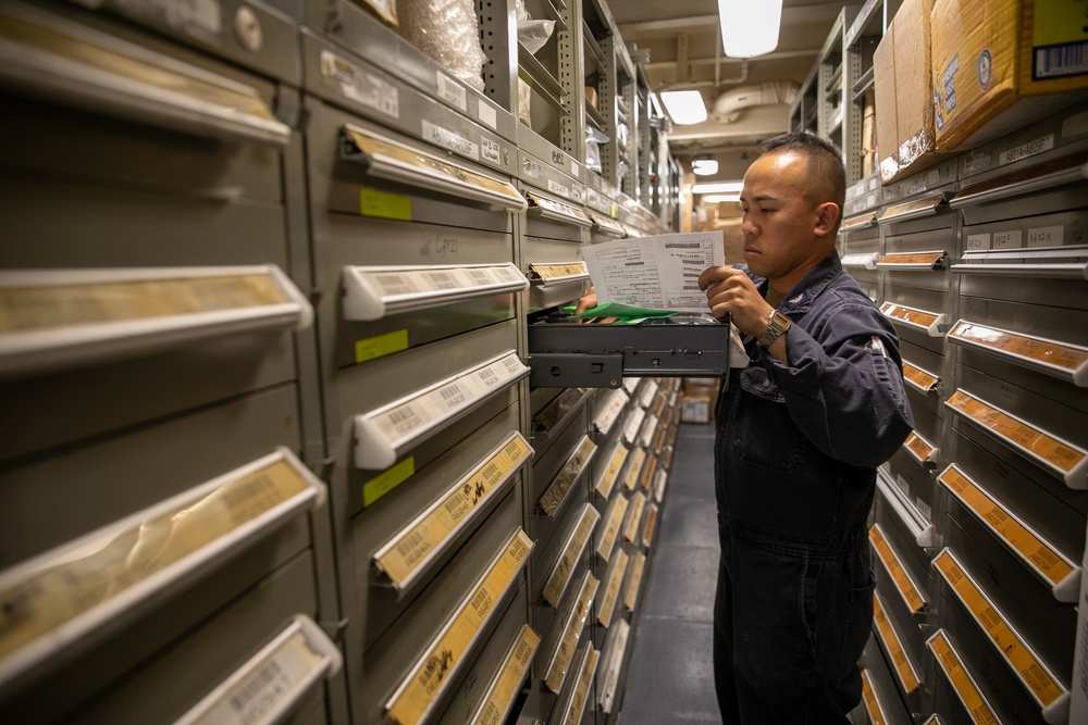 USS Mitscher (DDG 57) Sailor takes inventory in logistics storeroom