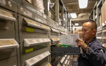 USS Mitscher (DDG 57) Sailor takes inventory in logistics storeroom
