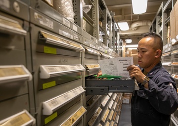 USS Mitscher (DDG 57) Sailor takes inventory in logistics storeroom