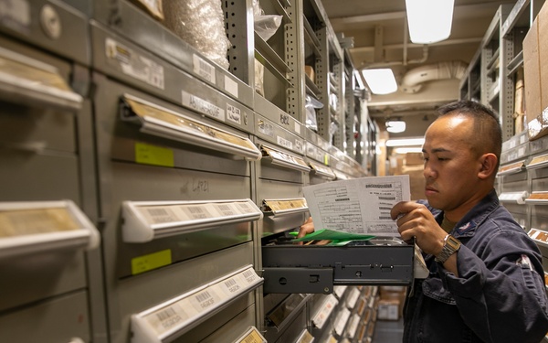 USS Mitscher (DDG 57) Sailor takes inventory in logistics storeroom