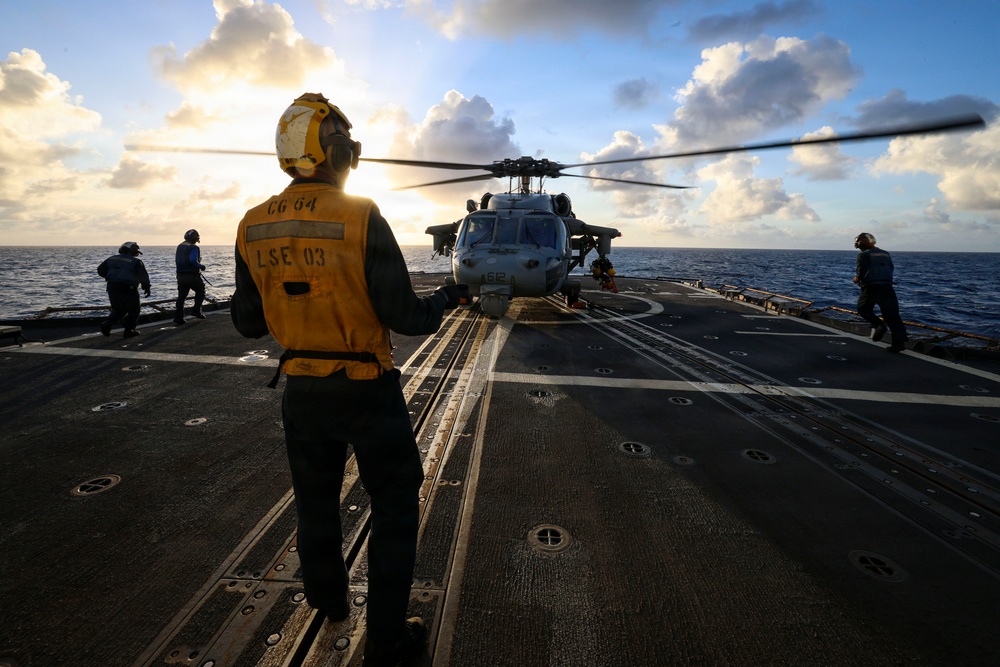 U.S. Sailor Signals Sailors to Chock and Chain an MH-60R Sea Hawk Helicopter