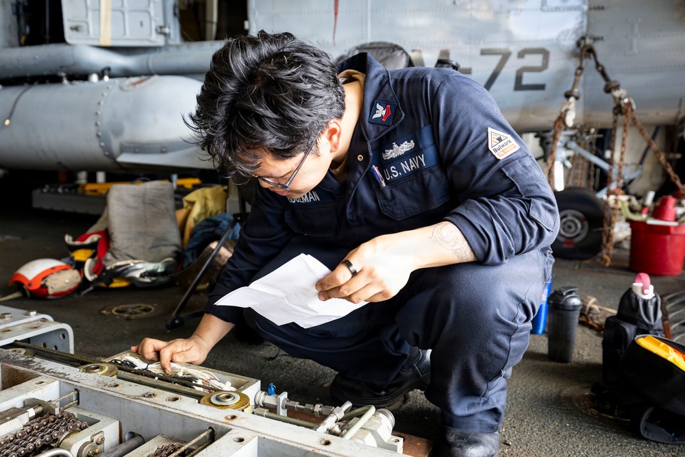 U.S. Sailor Conducts Routine Maintenance of a Rapid Securing Device in the Hangar Bay