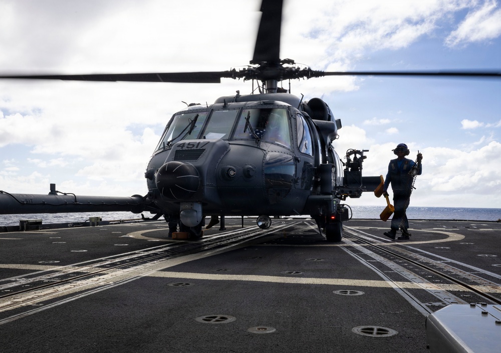 A U.S. Sailor Removes Chocks and Chains From a U.S. Air Force HH-60W Pave Hawk Helicopter on the Flight Deck