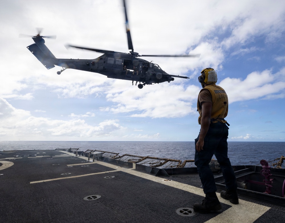 A U.S. Sailor Signals to a U.S. Air Force HH-60W Pave Hawk Helicopter After Takeoff From the Flight Deck