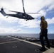 A U.S. Sailor Signals to a U.S. Air Force HH-60W Pave Hawk Helicopter After Takeoff From the Flight Deck